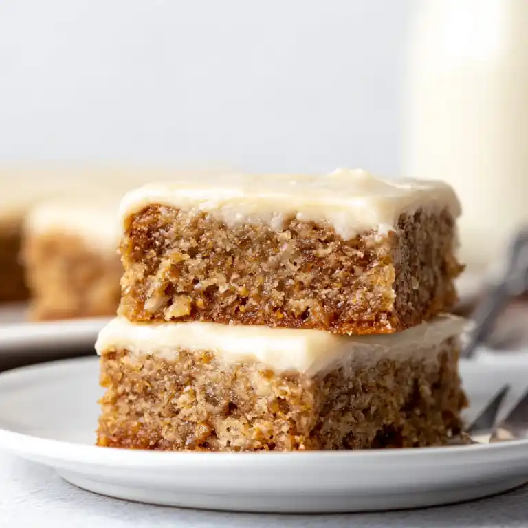 Banana bars with cream cheese frosting stacked on plate